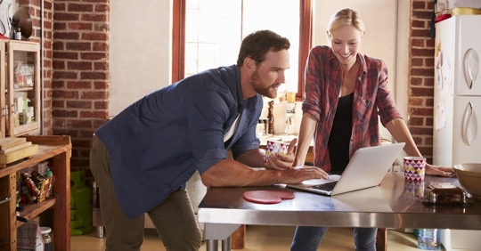 man and woman look at computer